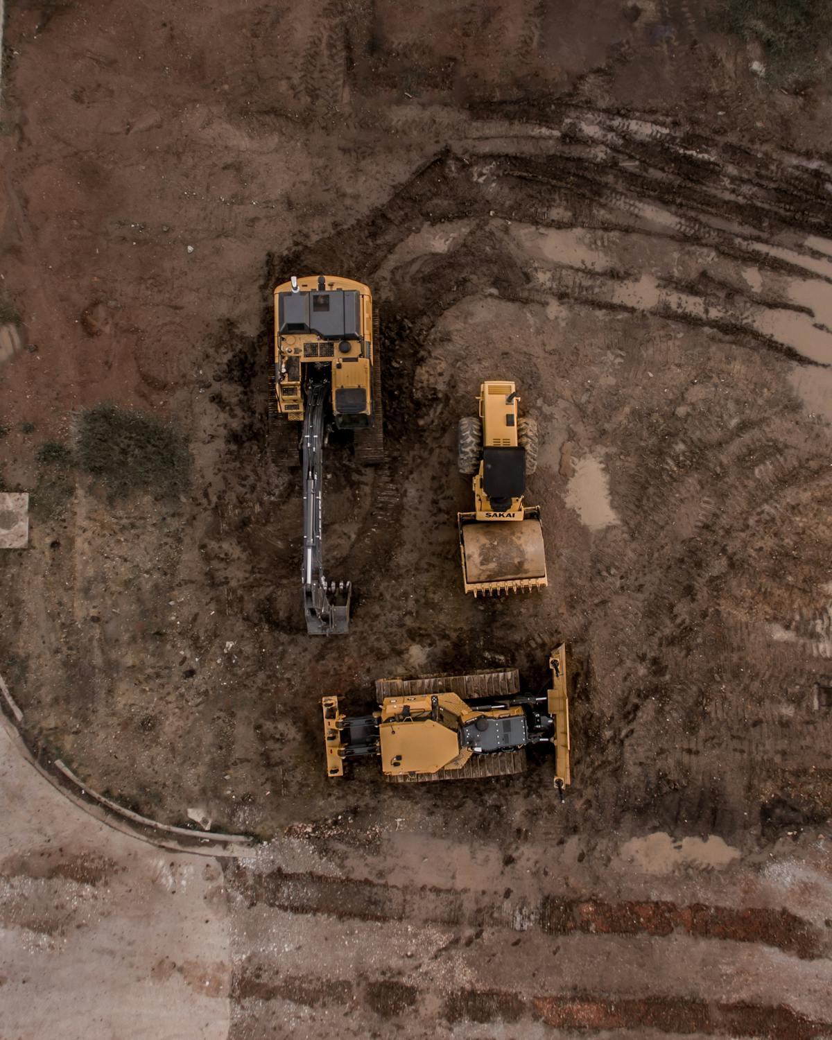 An aerial view of dump trucks at an excavation site, emphasizing the need for secure maintenance solutions like BedLock systems.