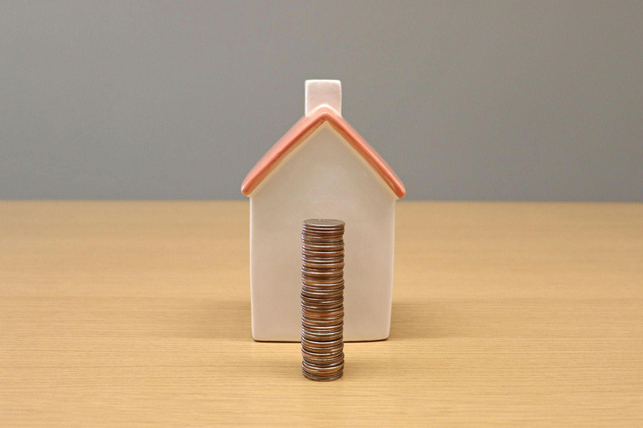 A miniature house placed next to coins