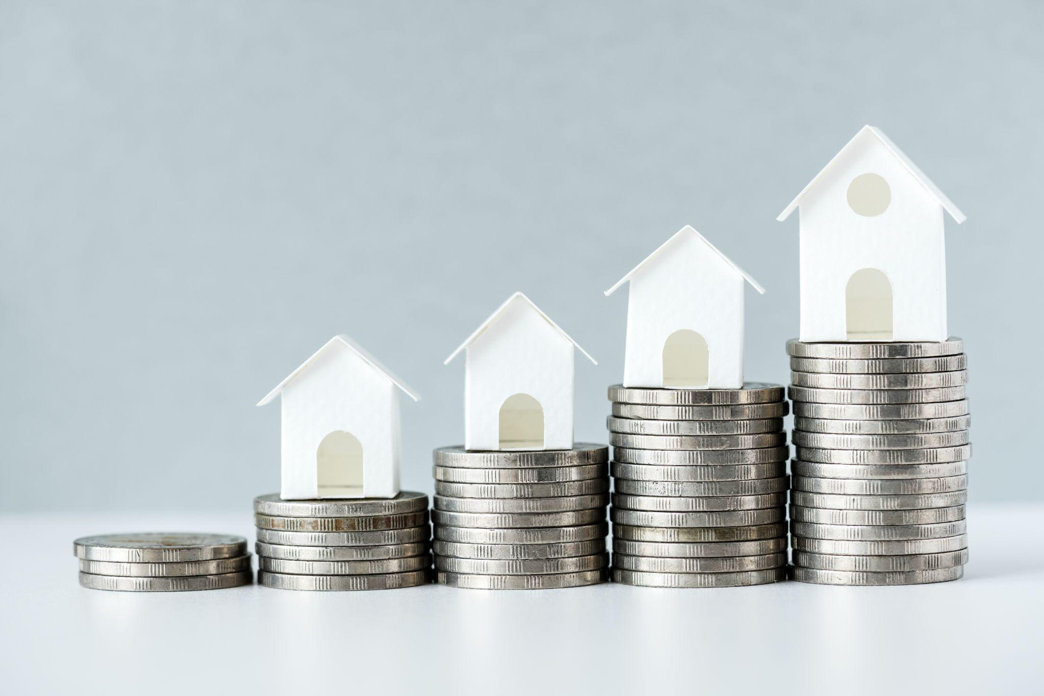 Miniature houses placed on top of stacked coins