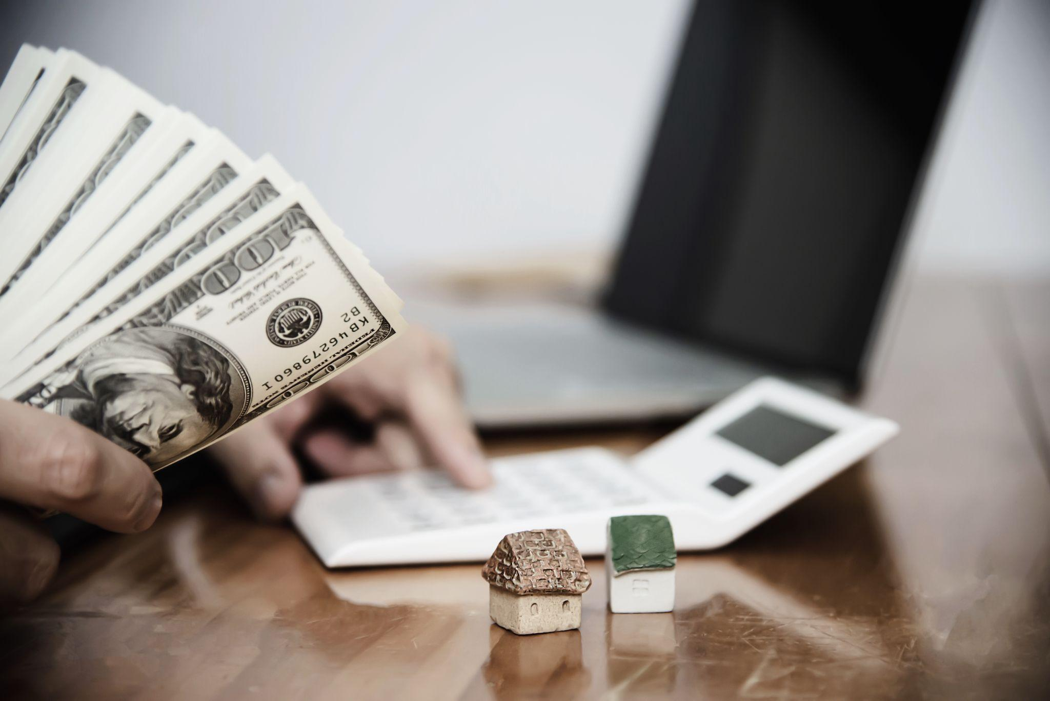 A miniature house with money and a calculator