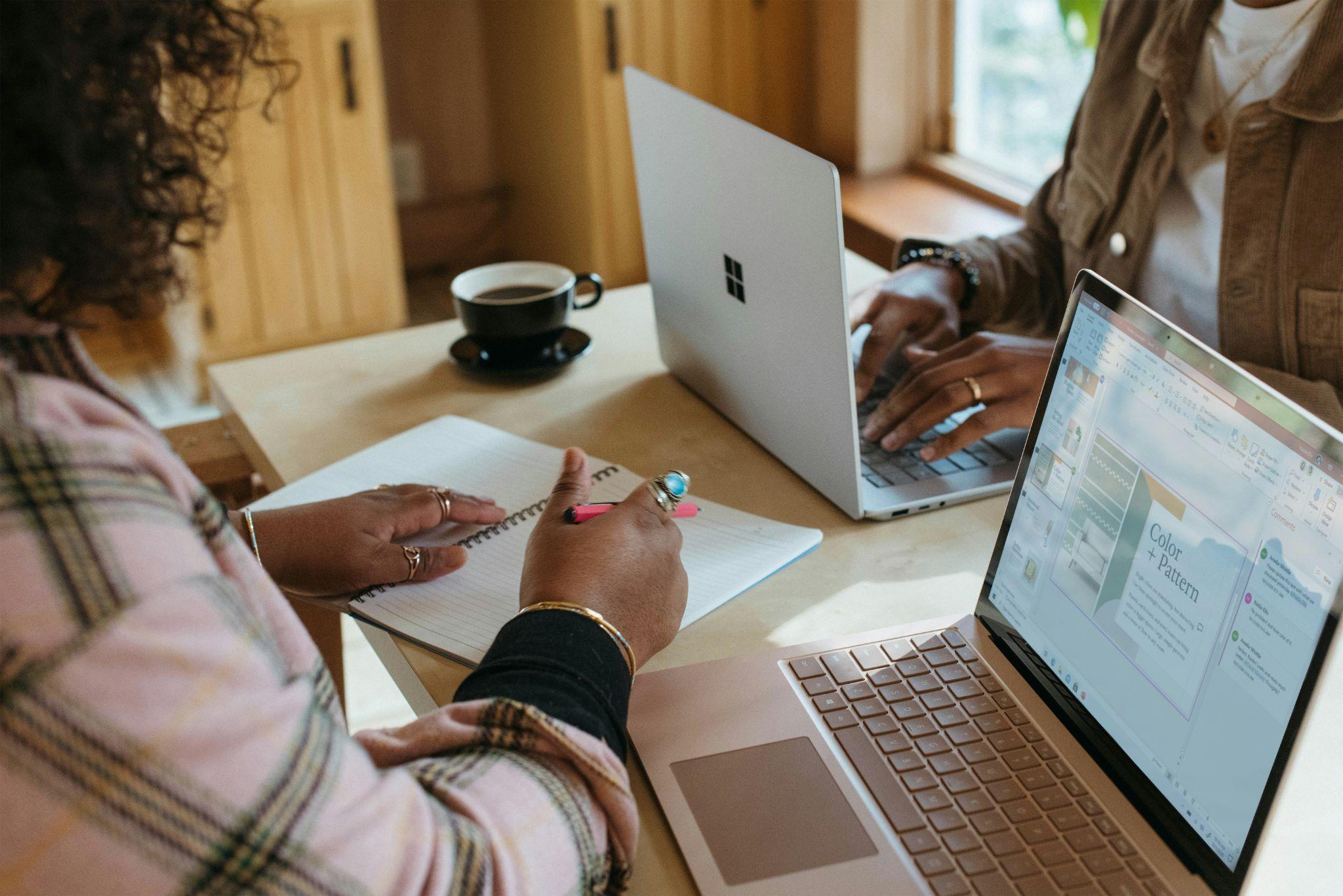 two women seated at a table and working on their laptops