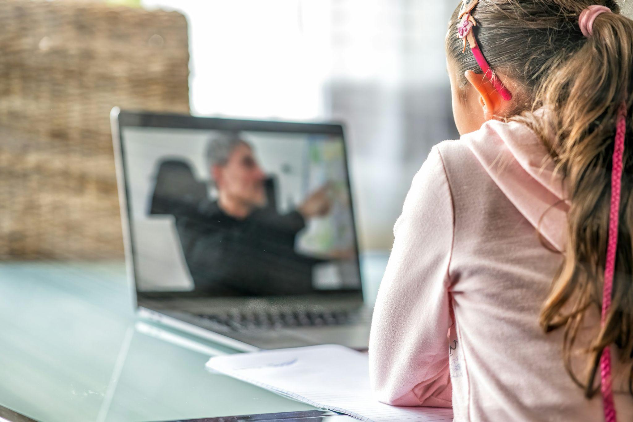a girl in pink clothing studying on a laptop