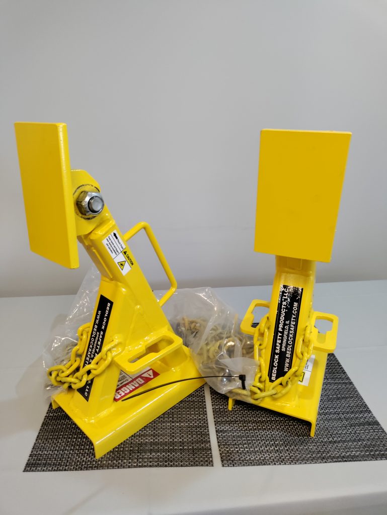Pair of BedLock dump truck bed safety devices on a workshop table