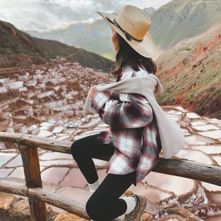a tourist posing sitting on a ledge at the Sacred Valley