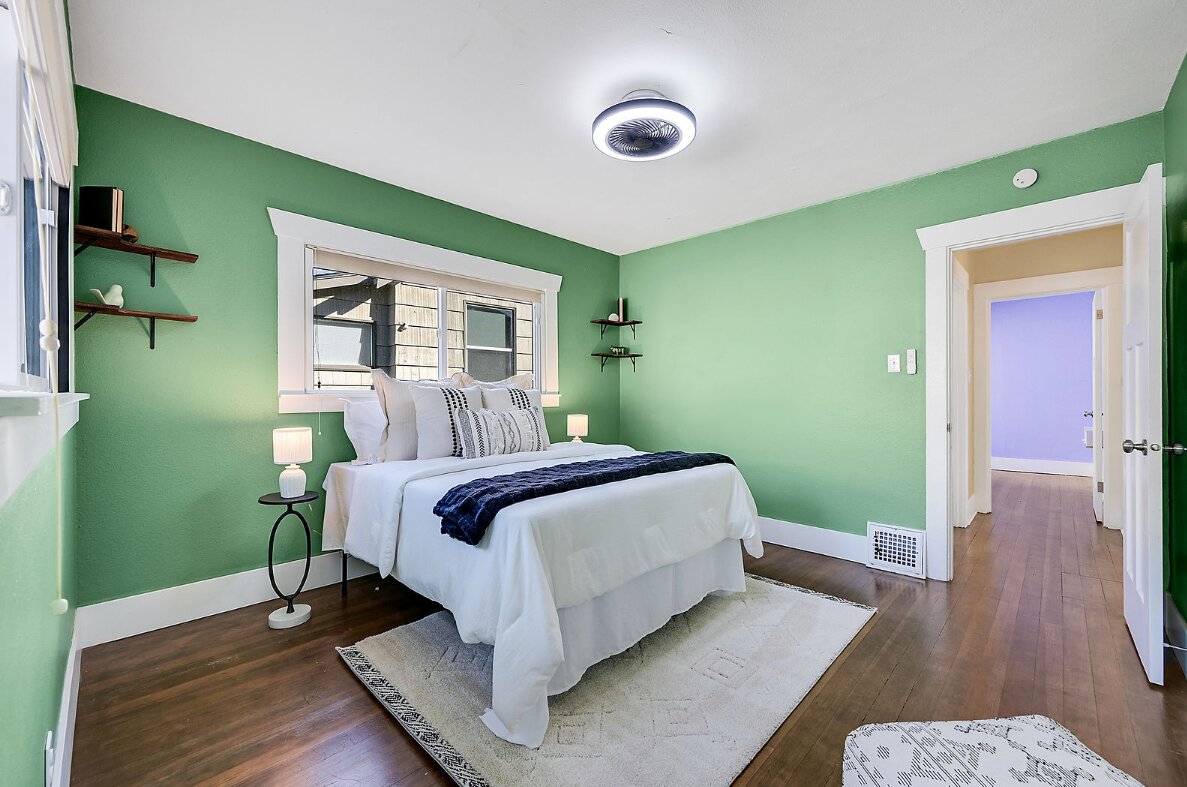 A bedroom with green walls and wood flooring