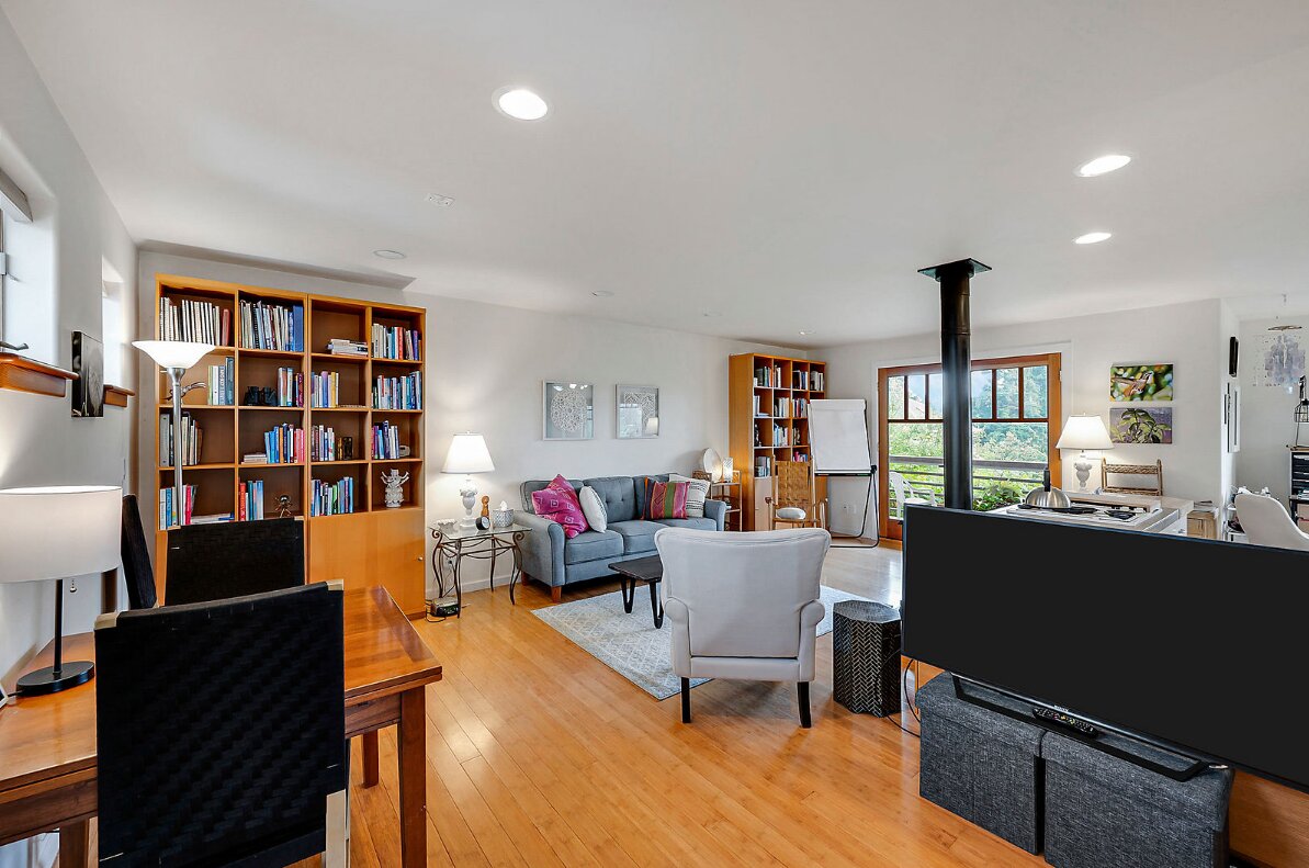 An open living room with wood floors, a seating area, and shelving