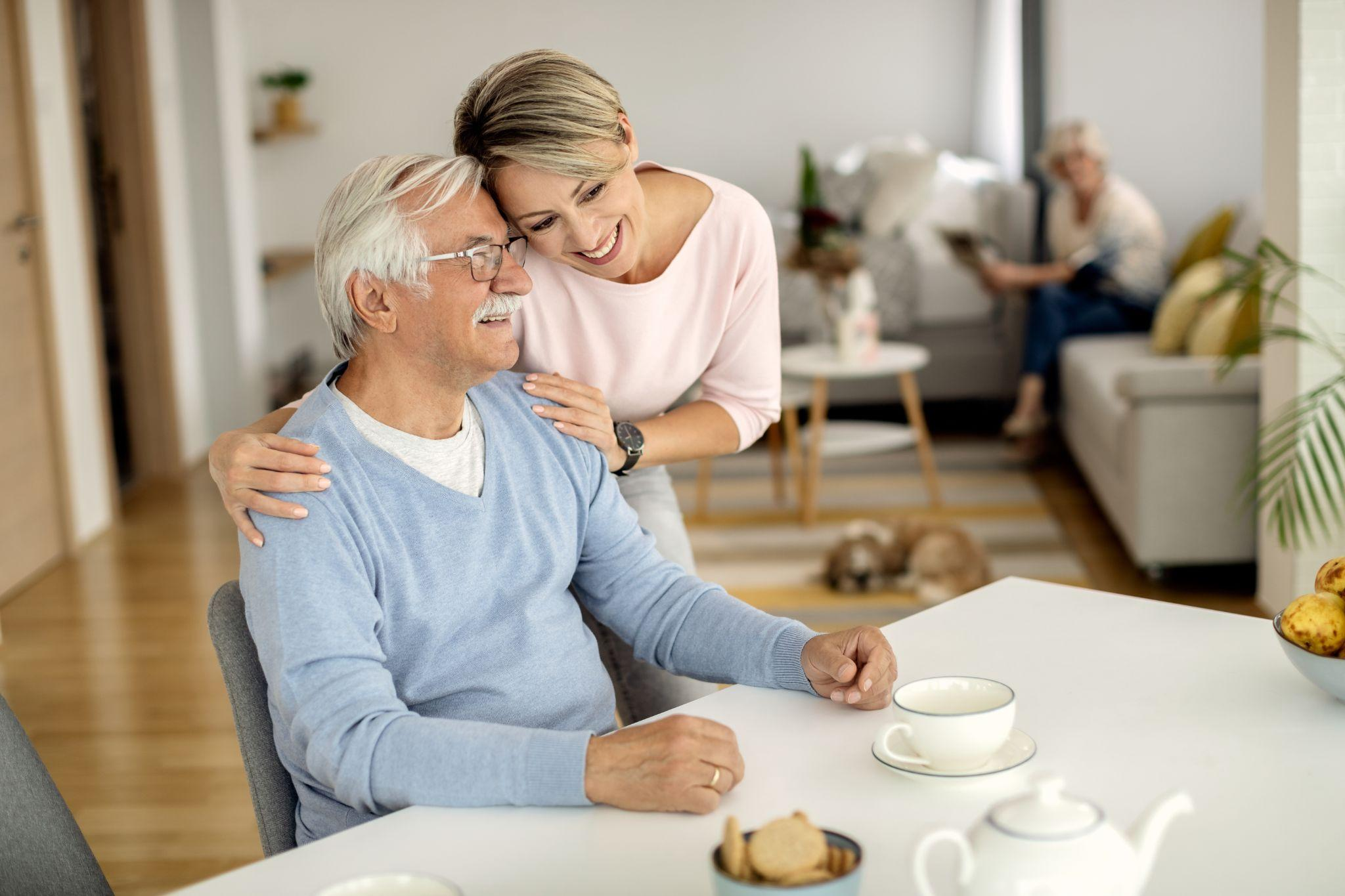 family member comforting and supporting an elderly man at home during a daily care routine