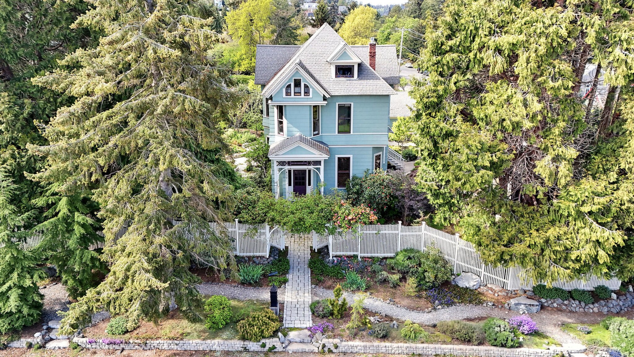 An aerial view of a unique blue house surrounded by trees.