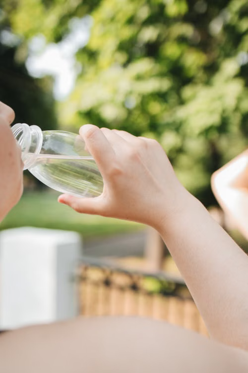 Person drinking water outdoors after an acupuncture wellness session during summer
